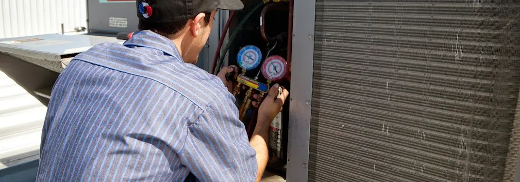HVAC technician servicing a condenser unit in Brooklyn Park